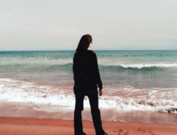 Frau am Strand schaut raus aufs Meer